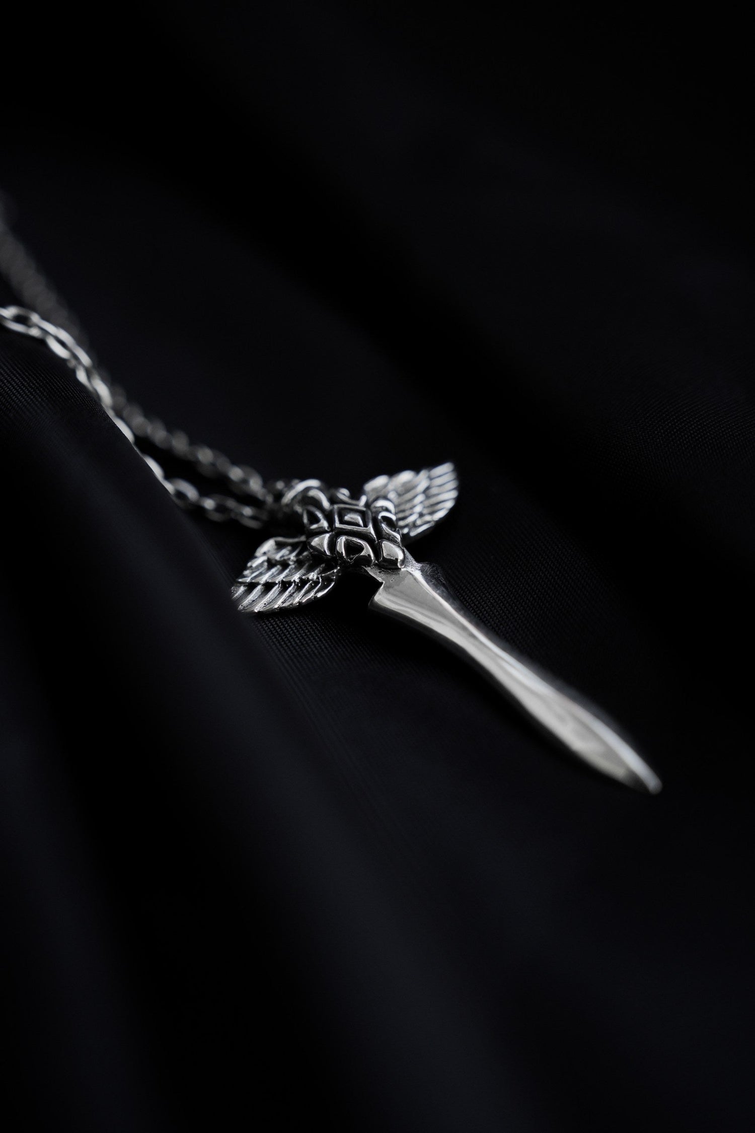 Silver pendant with angel wings and amethyst gemstone on a black background, festival jewelry by NEBULA.